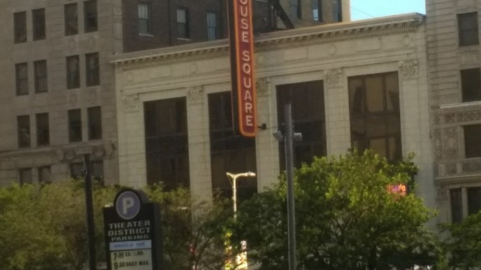 Exterior view of urban street with multiple brick buildings, vehicles, and nearby Payhouse Square signage