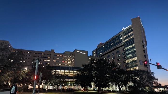Exterior view of illuminated Ochsner facility buildings at dusk with signage and landscaping