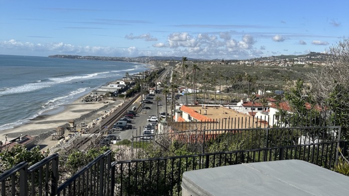 Exterior oceanfront deck featuring hot tub, metal railing, lounge seating overlooking San Clemente beach and Pacific Ocean