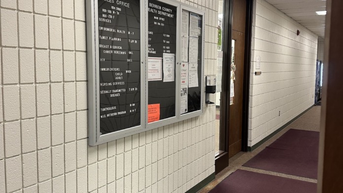 Interior hallway wall with office information display boards listing department services and hours