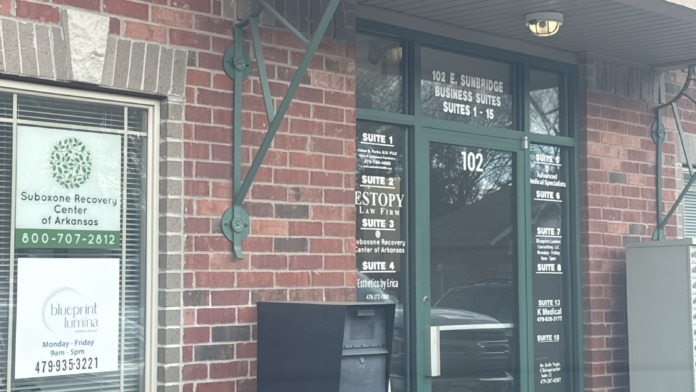 Interior entrance showing wooden framed glass door with facility signage and modern office reception area visible