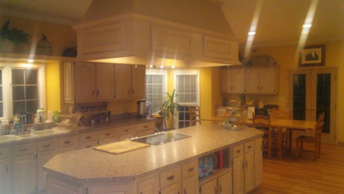 Interior large kitchen with yellow walls, island countertop, dining furniture, and open living space