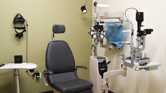 Interior optometry exam room with phoropter equipment, patient chair, and diagnostic instrumentation