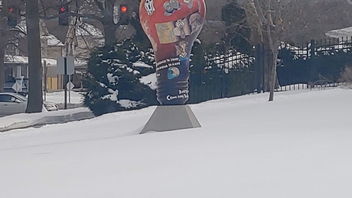 Exterior view of decorative red hot air balloon sculpture in snowy courtyard area with bare trees and fencing visible