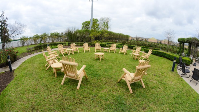 Outdoor recreational space with Adirondack chairs arranged in circle formation on grass for group activities