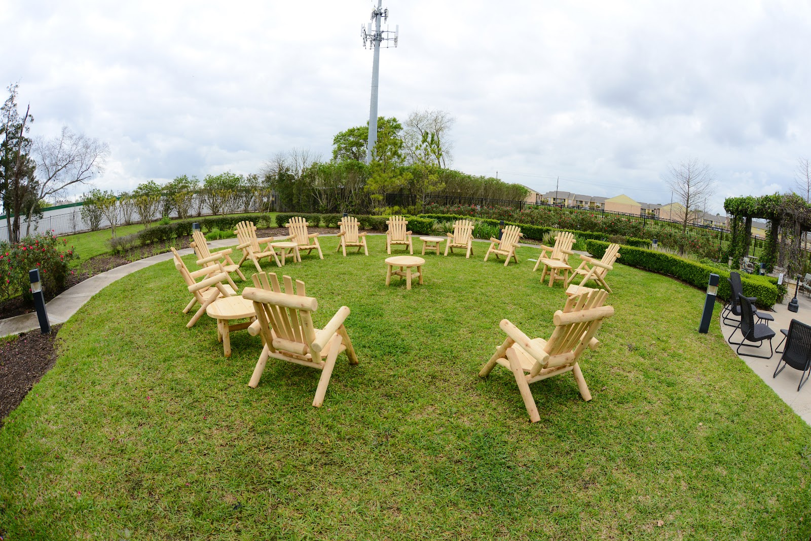 Outdoor recreational space with Adirondack chairs arranged in circle formation on grass for group activities