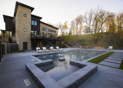 Outdoor amenity area featuring modern fire pit, swimming pool, lounge chairs, and natural grounds with trees