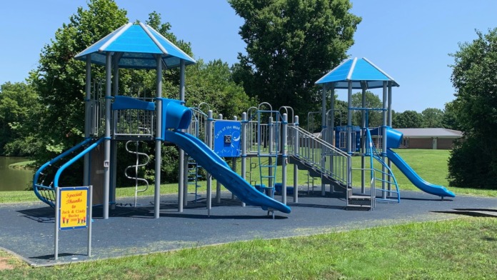 Exterior playground featuring blue climbing structures, slides, and recreational equipment on groomed grounds