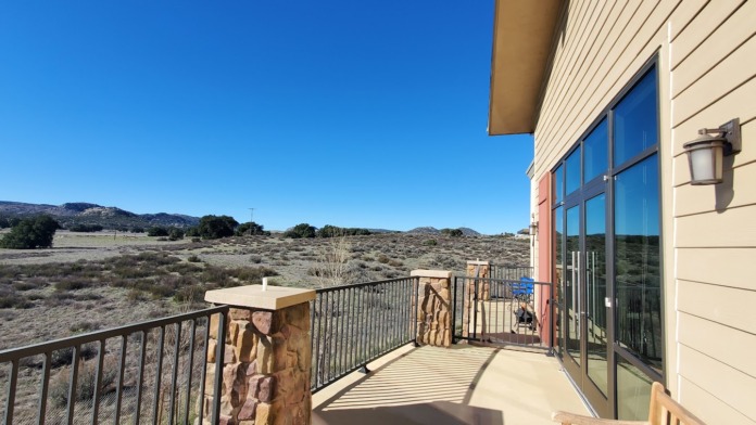 Exterior deck area with metal railings, table seating, and scenic desert mountain landscape