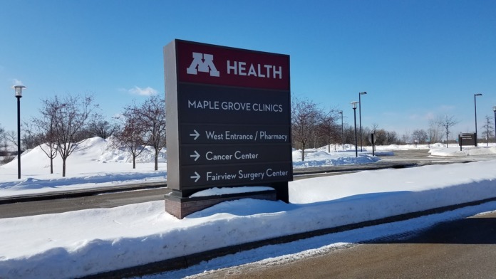 Exterior view of M Health Fairview signage indicating Maple Grove Clinics, Cancer Center, and Surgery Center locations with snowy landscape
