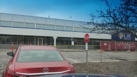 Exterior view of modern medical facility building with parking lot, glass windows, and UR Medicine branding visible