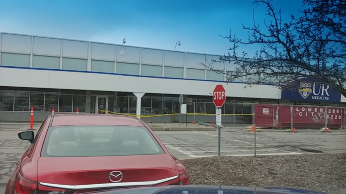 Exterior view of modern medical facility building with parking lot, glass windows, and UR Medicine branding visible