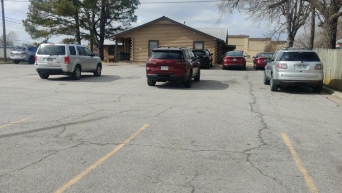 Exterior view of parking lot with multiple vehicles parked in front of log cabin-style treatment facility building