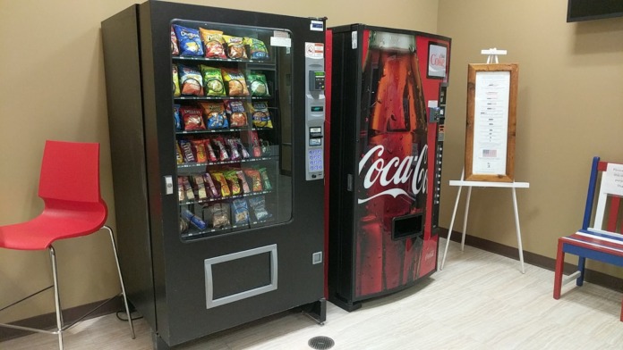 Interior vending area with snack and beverage machines, red chairs, and informational signage