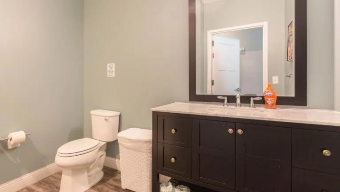 Interior bathroom with vanity, mirror, toilet, and tasteful neutral decor with accessible design features