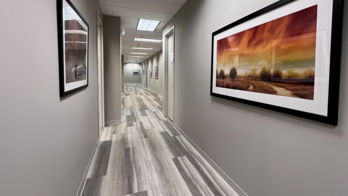 Interior patient bedroom with multiple beds, decorative wall art, bedside furniture, and warm ambient lighting
