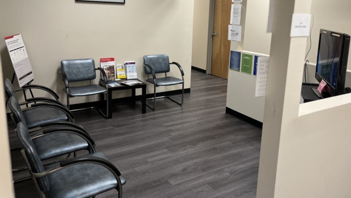 Interior reception area with waiting chairs, check-in counter, and educational materials displayed on walls
