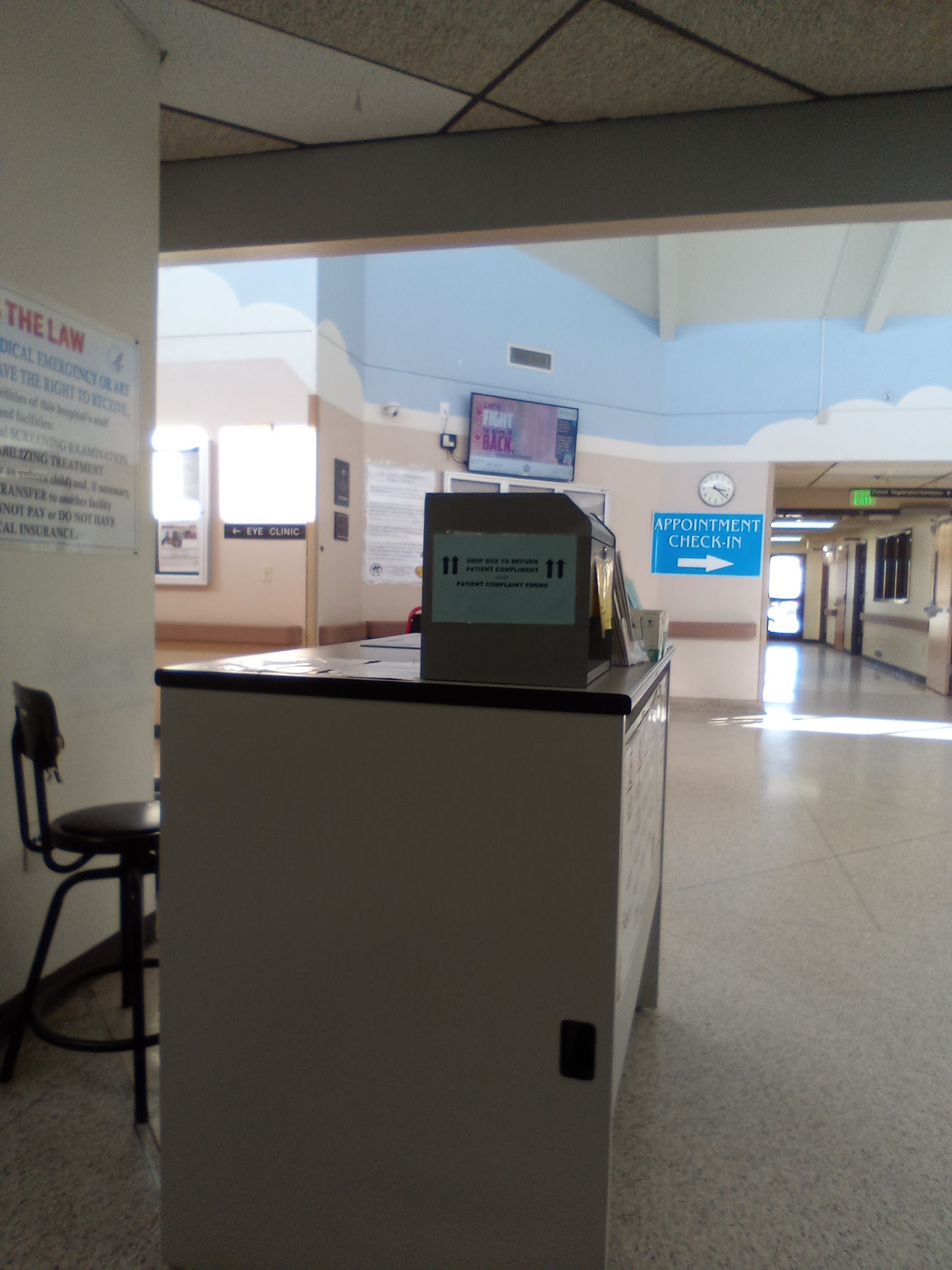 Interior waiting room with check-in desk featuring electronic display, appointment signage, and patient seating