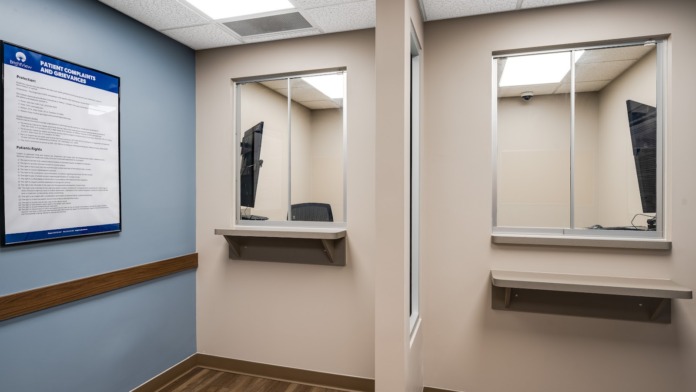 Interior intake office with consultation windows, patient information signage, and waiting area seating