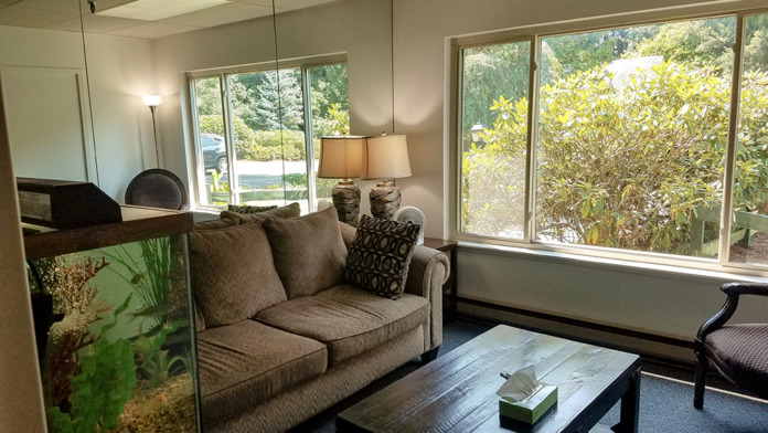 Interior lounge space with comfortable seating furniture, windows with forest views, aquarium, and natural lighting