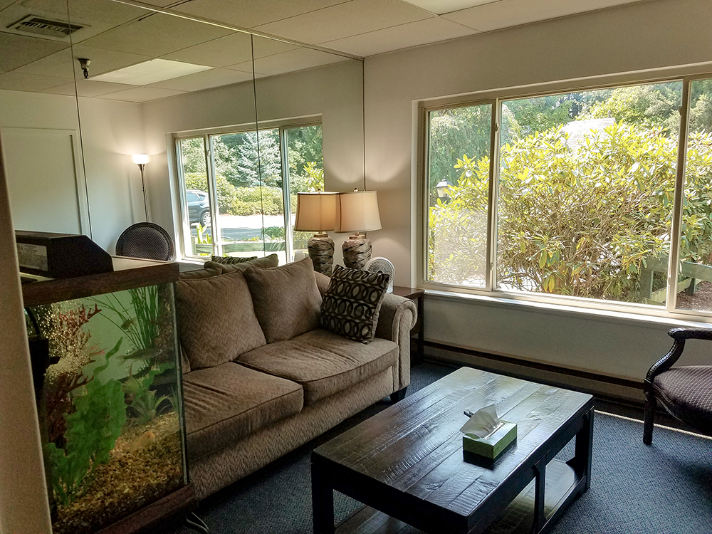 Interior lounge space with comfortable seating furniture, windows with forest views, aquarium, and natural lighting