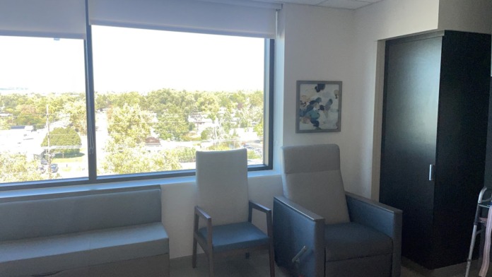 Interior patient lounge with comfortable seating, large window overlooking city, modern furnishings, and wall artwork