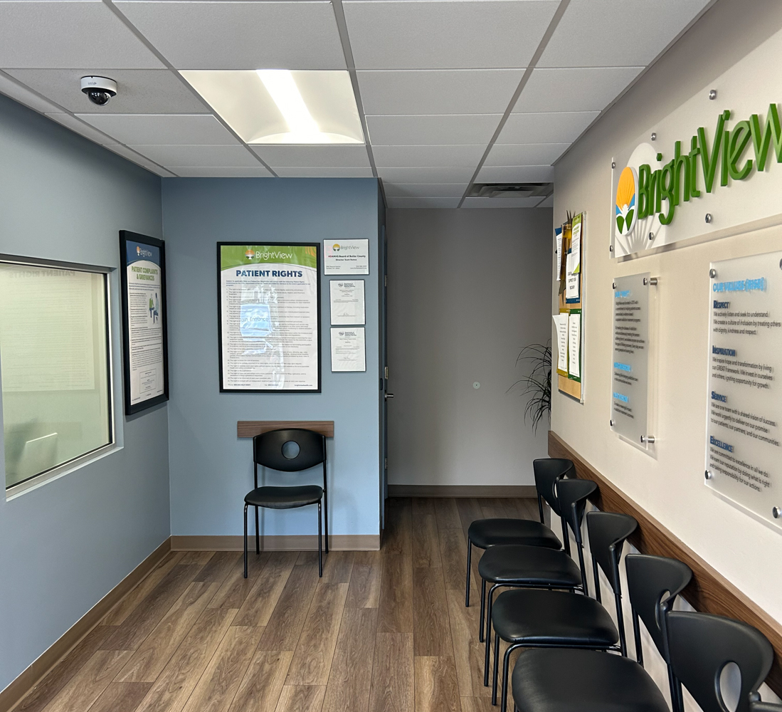 Interior reception area with blue walls, black chairs, informational posters, and patient rights signage displayed.