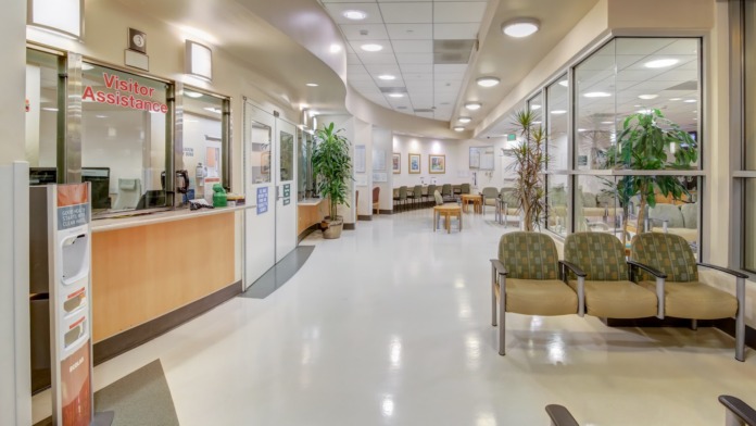 Interior lobby with reception desk, visitor assistance window, seating chairs, potted plants and polished flooring