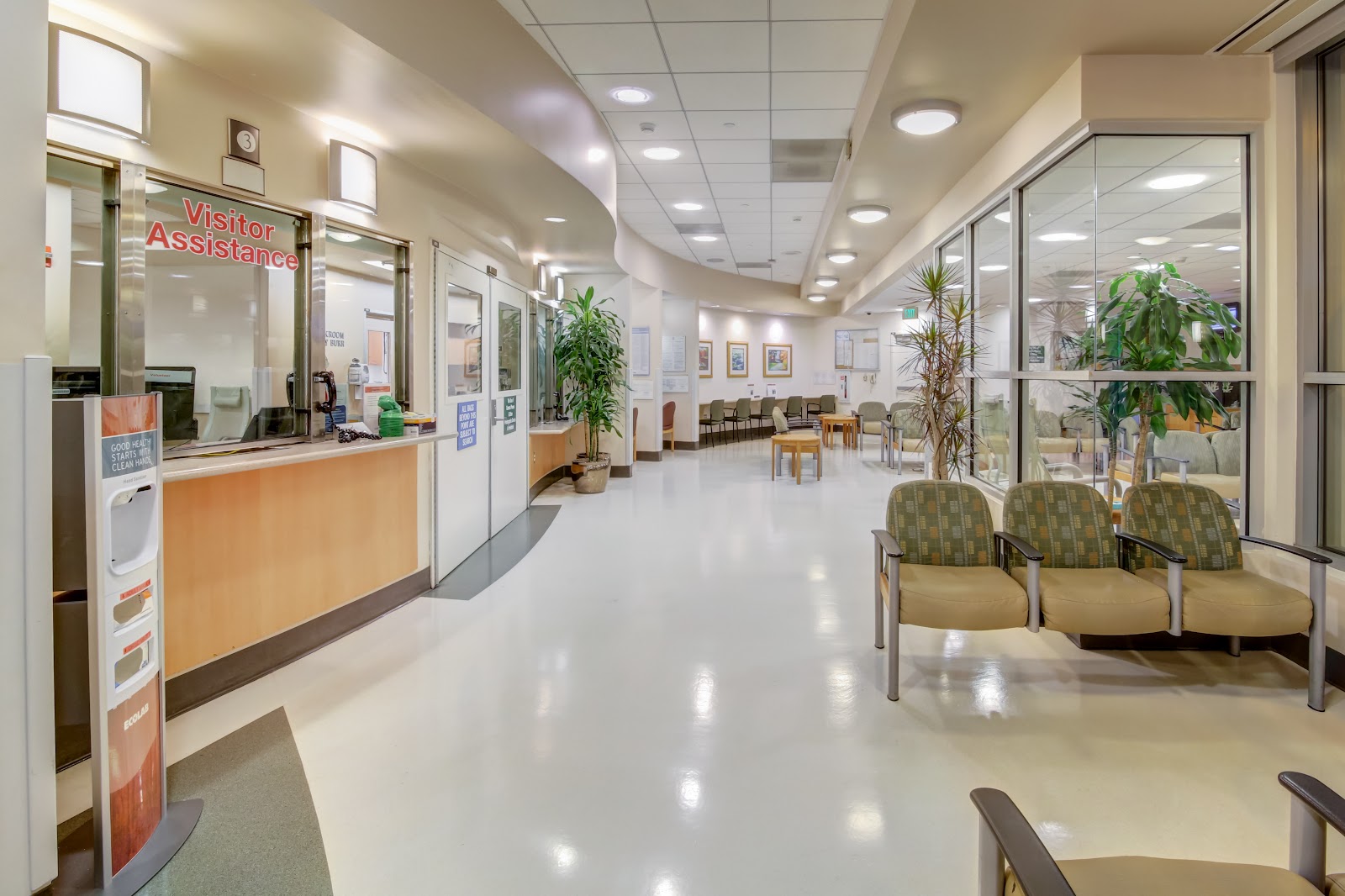 Interior lobby with reception desk, visitor assistance window, seating chairs, potted plants and polished flooring