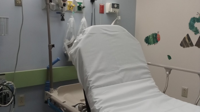 Interior patient treatment room with medical bed, equipment, monitoring devices, and child-friendly wall art