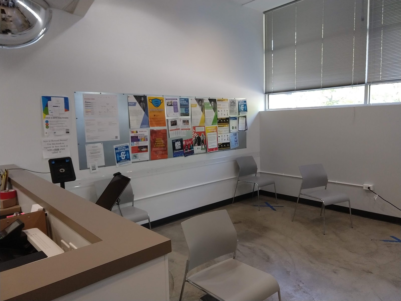 Interior waiting room with gray seating, information boards on walls, and window views to street