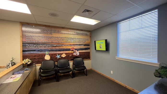 Interior waiting room with comfortable seating, inspirational starfish story mural on wall, television, and natural lighting from windows