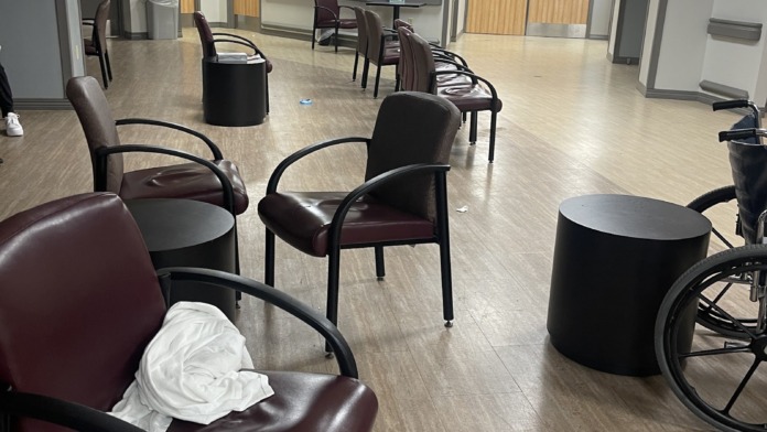 Interior waiting room with burgundy chairs, black side tables, modern flooring, and yellow door accents