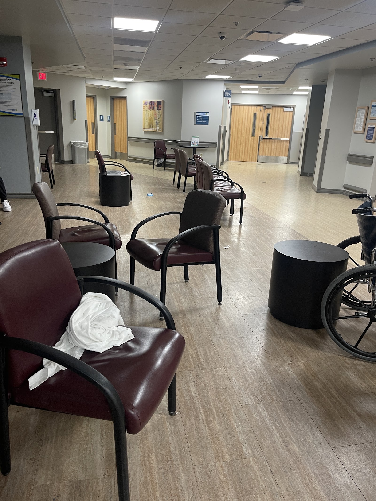 Interior waiting room with burgundy chairs, black side tables, modern flooring, and yellow door accents