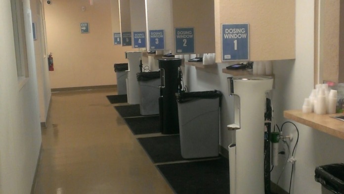 Interior medication preparation area with multiple labeled dosing windows, counter workspace, and fluorescent ceiling lights