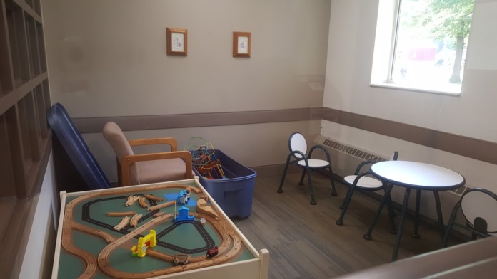 Interior playroom featuring wooden train track set, seating, and round table with chairs for recreational activities
