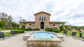 Outdoor recreational pool area with concrete deck, lounge chairs, and surrounding landscaping on facility grounds