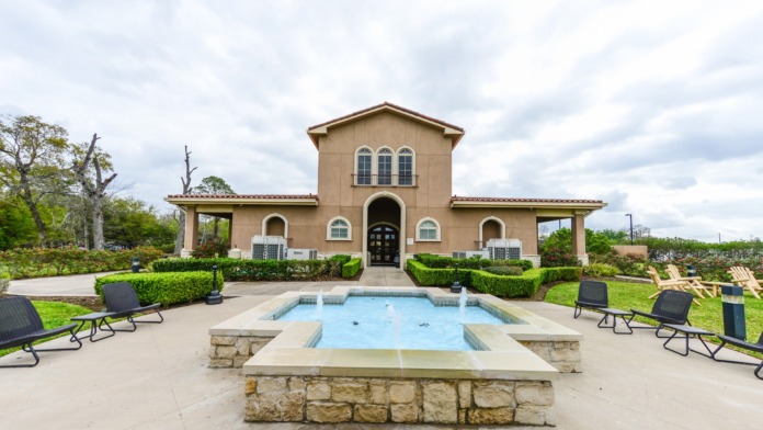 Outdoor recreational pool area with concrete deck, lounge chairs, and surrounding landscaping on facility grounds