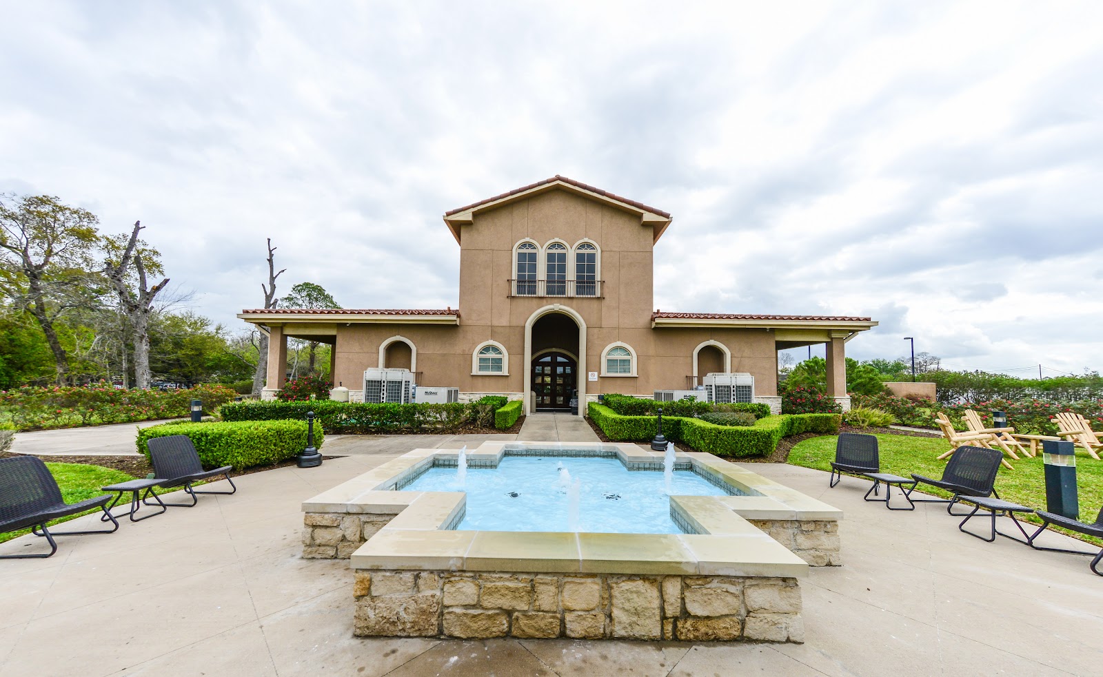 Outdoor recreational pool area with concrete deck, lounge chairs, and surrounding landscaping on facility grounds