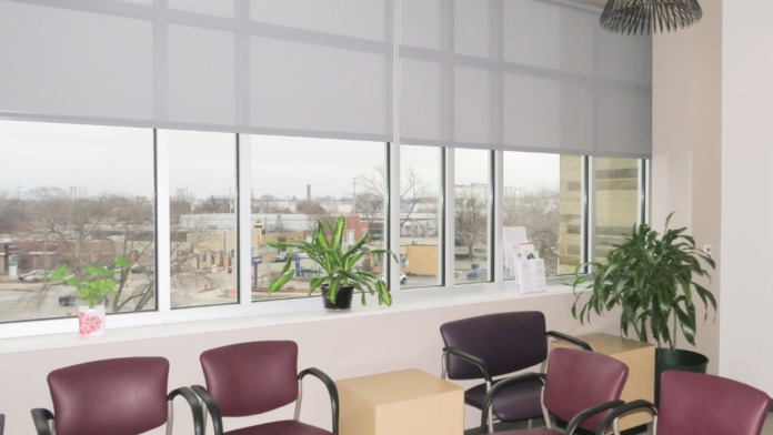 Interior check-in reception area with signage, burgundy wall panel, green seating chairs, and administrative desk workspace