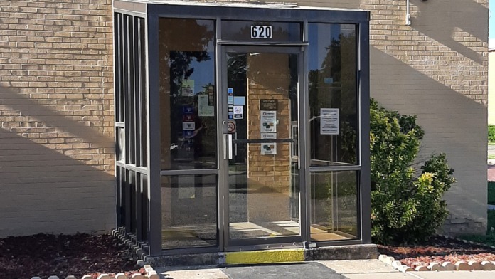 Exterior close-up of facility entrance showing glass door, vestibule area, and brick facade with address number 620