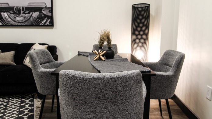 Interior meeting room with gray upholstered chairs, black table, and minimalist decor with text artwork.