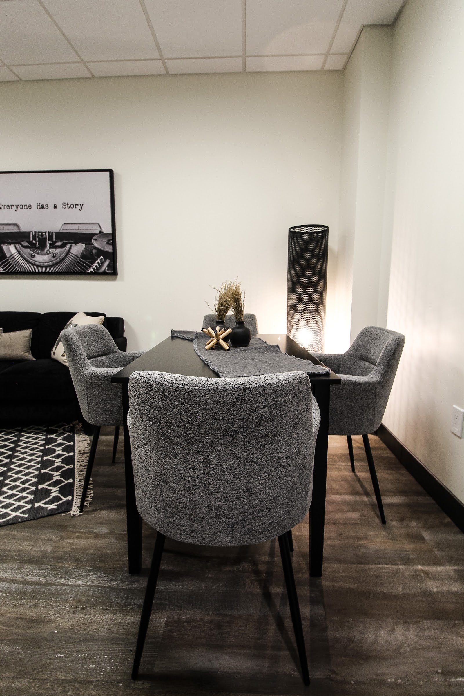 Interior meeting room with gray upholstered chairs, black table, and minimalist decor with text artwork.
