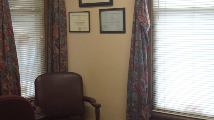 Interior private office with professional furnishings and framed certifications on walls