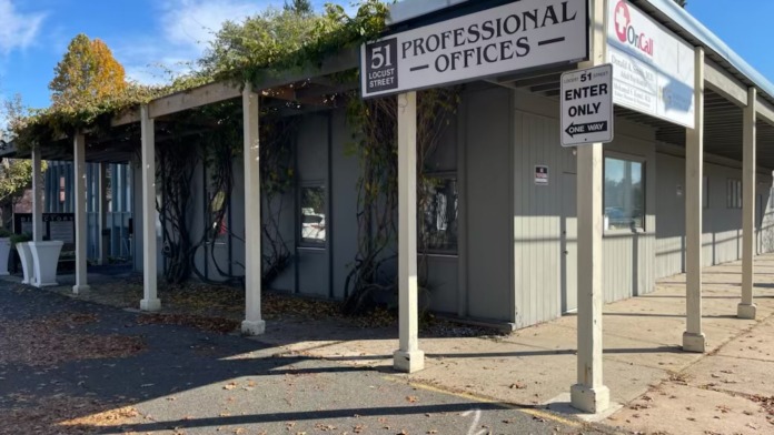 Exterior view of office entrance with covered canopy, ivy-covered facade, and directional signage on Locust Street