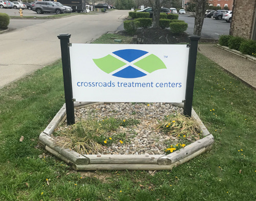 Outdoor signage showing Crossroads Treatment Centers logo with landscaping and facility building in background