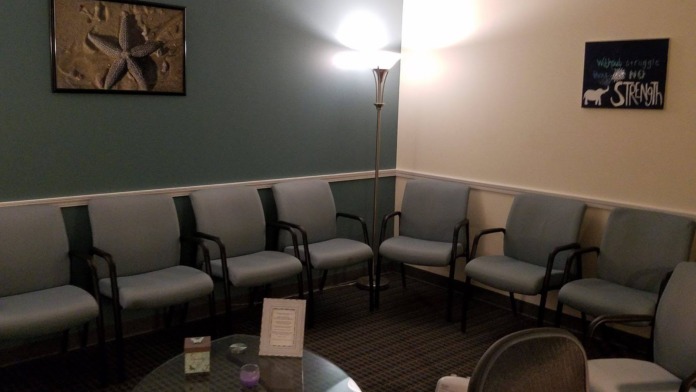 Interior reception seating with gray upholstered chairs, inspirational signage, and starfish artwork on walls