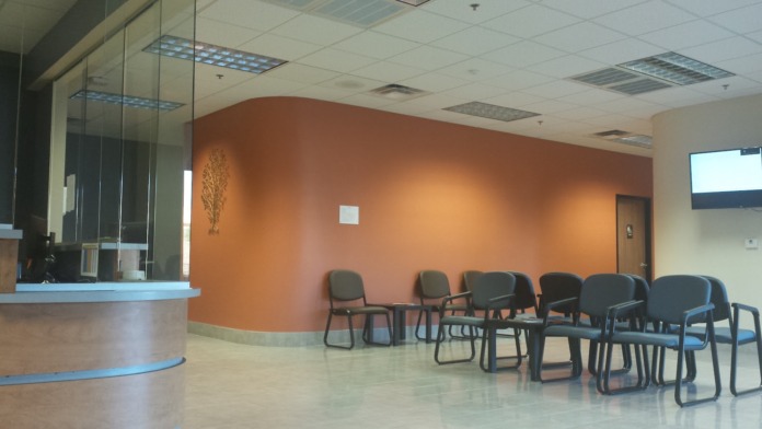 Interior reception desk with orange accent wall, waiting seating, and clean modern design