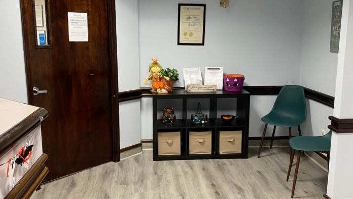 Interior reception area with storage shelving, office door, decorative items, and comfortable seating