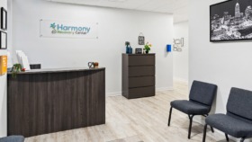 Interior reception area featuring Harmony Recovery Center logo on wall, dark wood desk, seating, and decorative elements